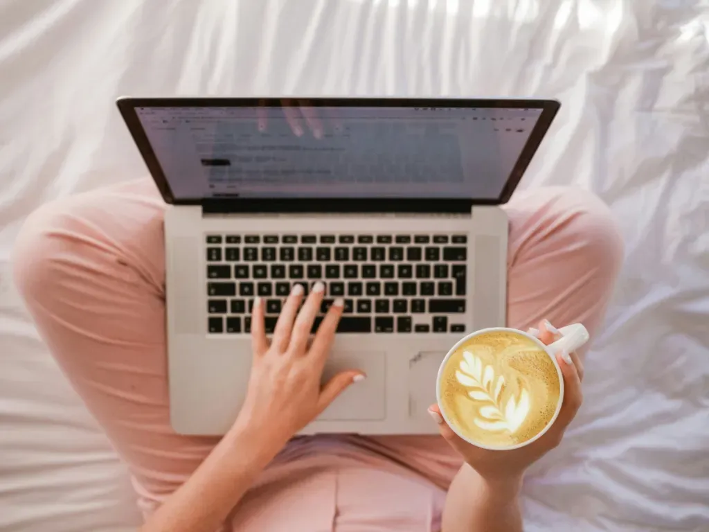 Woman working on laptop with coffee in a cozy setting